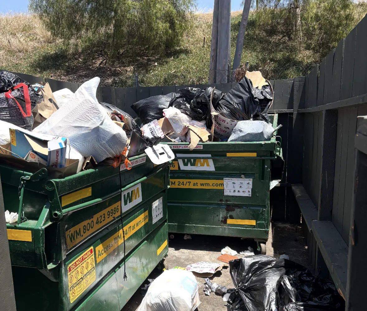 Full dumpsters at a condo complex on a weekly pickup