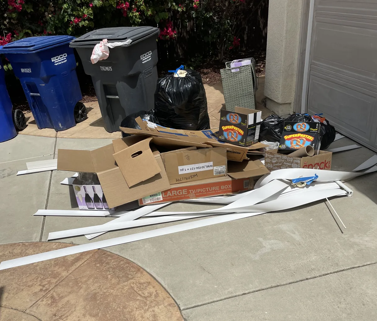 Broken-down boxes, trash bags and old trim piled in the driveway outside a garage