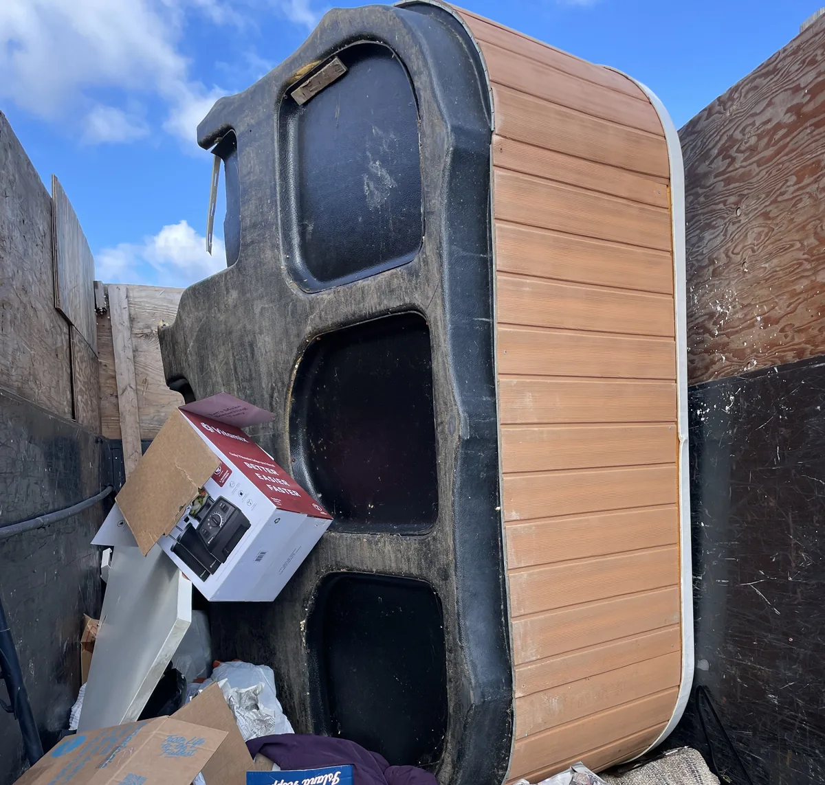 Hot tub shell standing on end in the loaded dump trailer