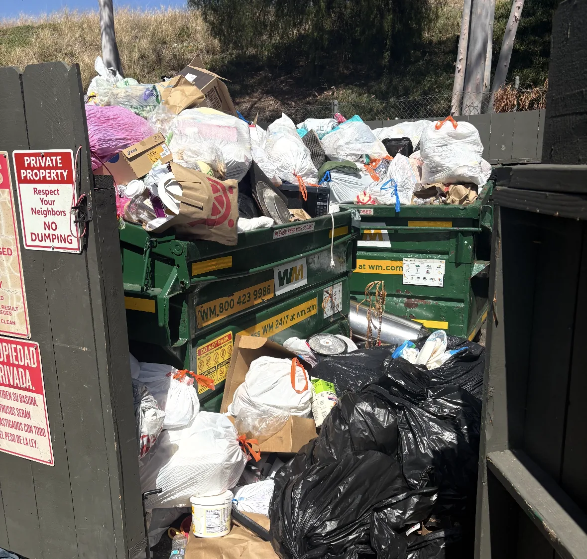 Overflowing dumpster enclosure at a North County condo complex