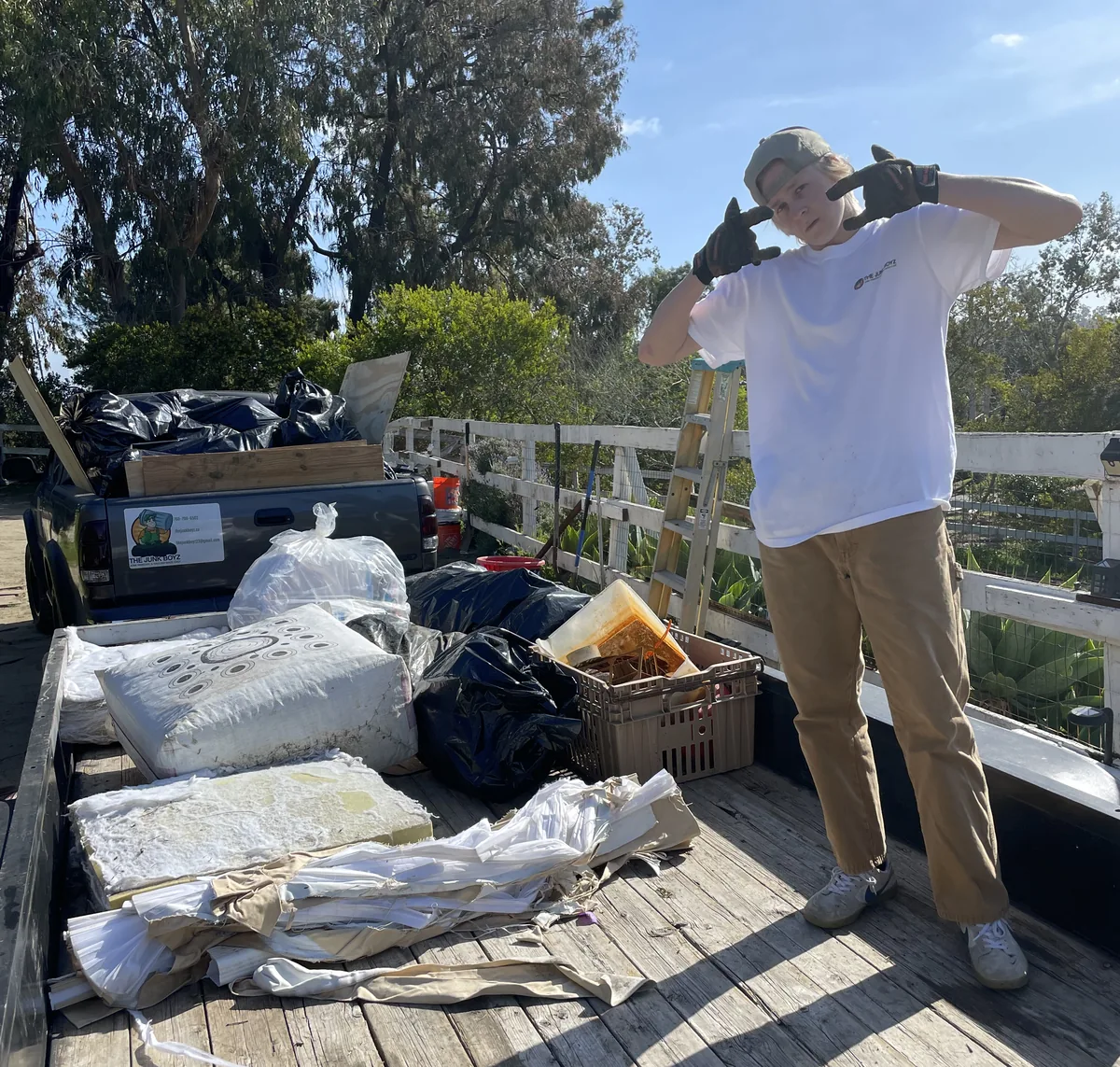 Chris standing on the loaded trailer next to mattresses and bagged junk