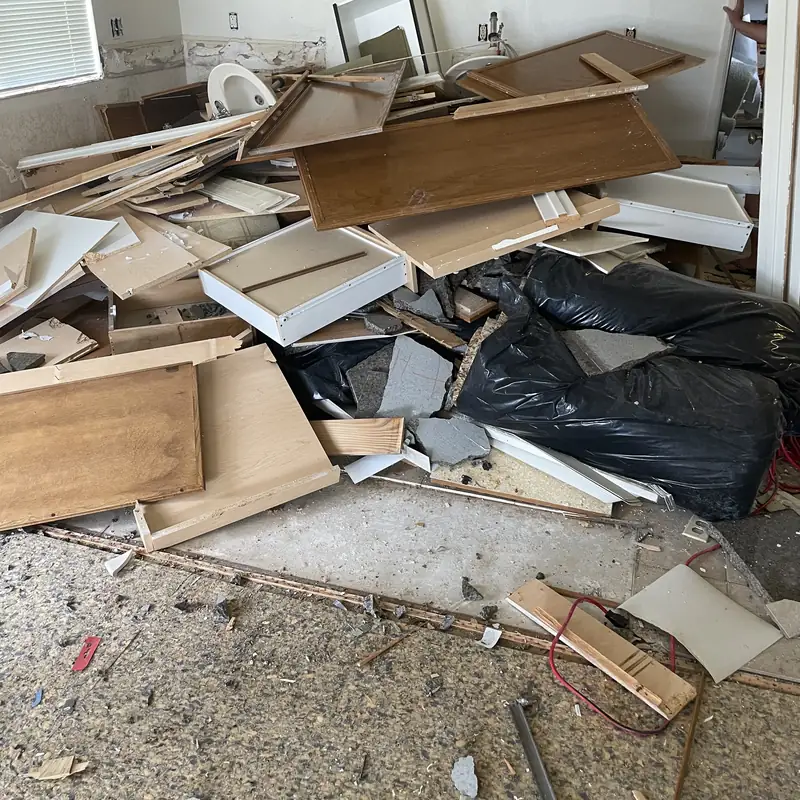 Torn out cabinets, lumber and drywall piled in a gutted kitchen