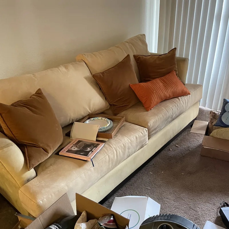 Tan couch with cushions in a living room, ready to be hauled out